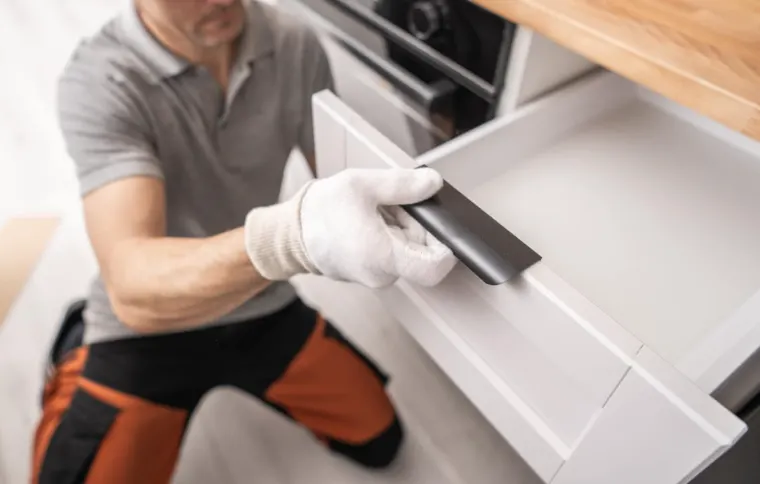 Cabinet maker installing a new cabinet door during a kitchen renovation